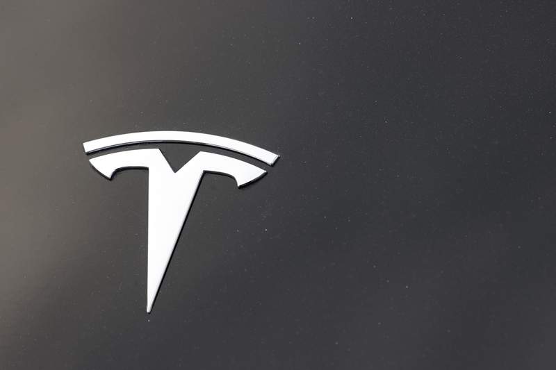 the company logo is seen on the hood of an unsold tesla at a